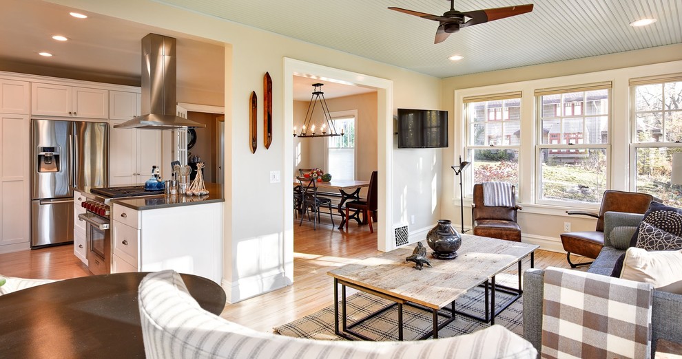 Ejemplo de sala de estar abierta clásica renovada de tamaño medio con paredes grises, suelo de madera clara y televisor colgado en la pared