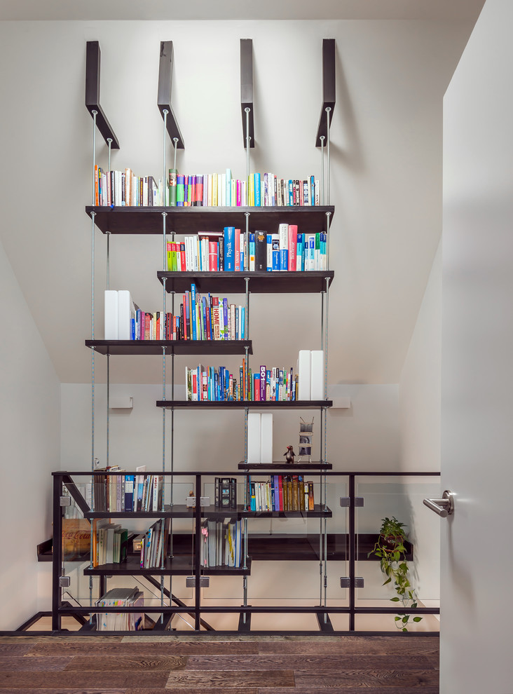 Idée de décoration pour une salle de séjour design ouverte avec une bibliothèque ou un coin lecture, un mur blanc et parquet foncé.