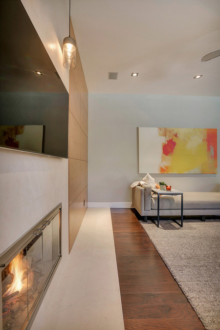 Diseño de sala de estar abierta contemporánea grande con paredes grises, suelo de madera oscura, todas las chimeneas, marco de chimenea de piedra y televisor colgado en la pared