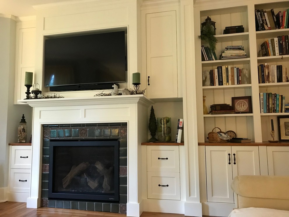 Ejemplo de sala de estar tradicional renovada de tamaño medio con paredes grises, suelo de madera en tonos medios, todas las chimeneas, marco de chimenea de baldosas y/o azulejos, pared multimedia y suelo marrón