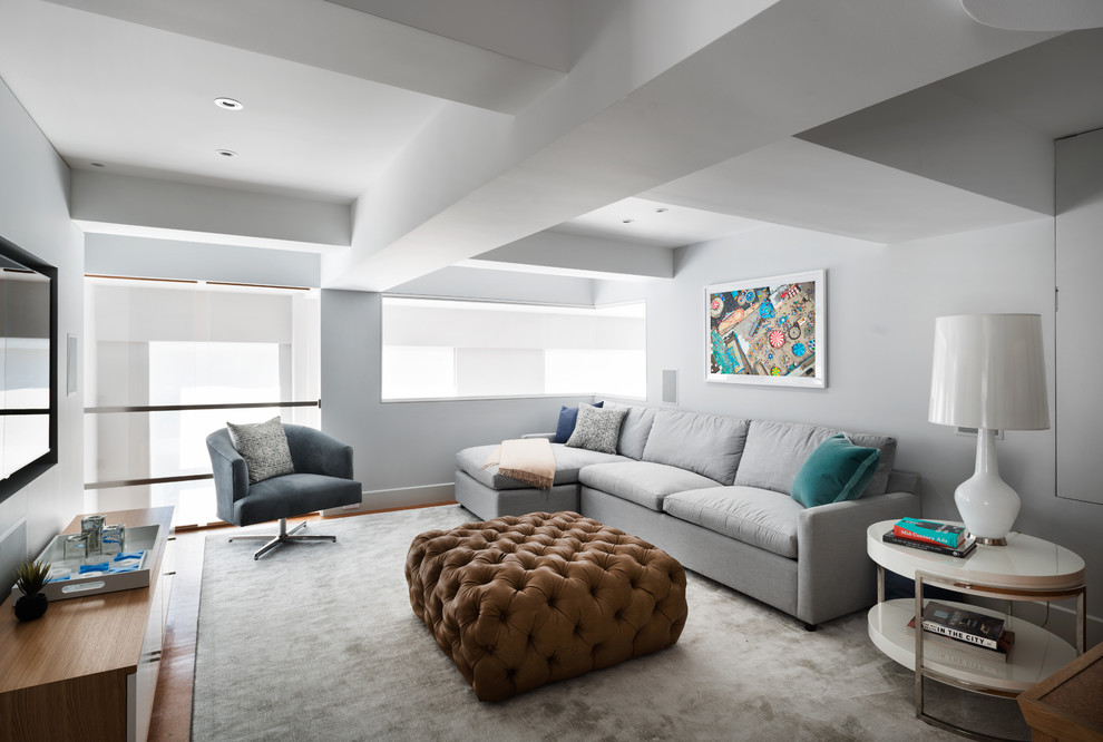 Foto de sala de estar tipo loft contemporánea de tamaño medio con paredes grises, suelo de madera clara y televisor colgado en la pared