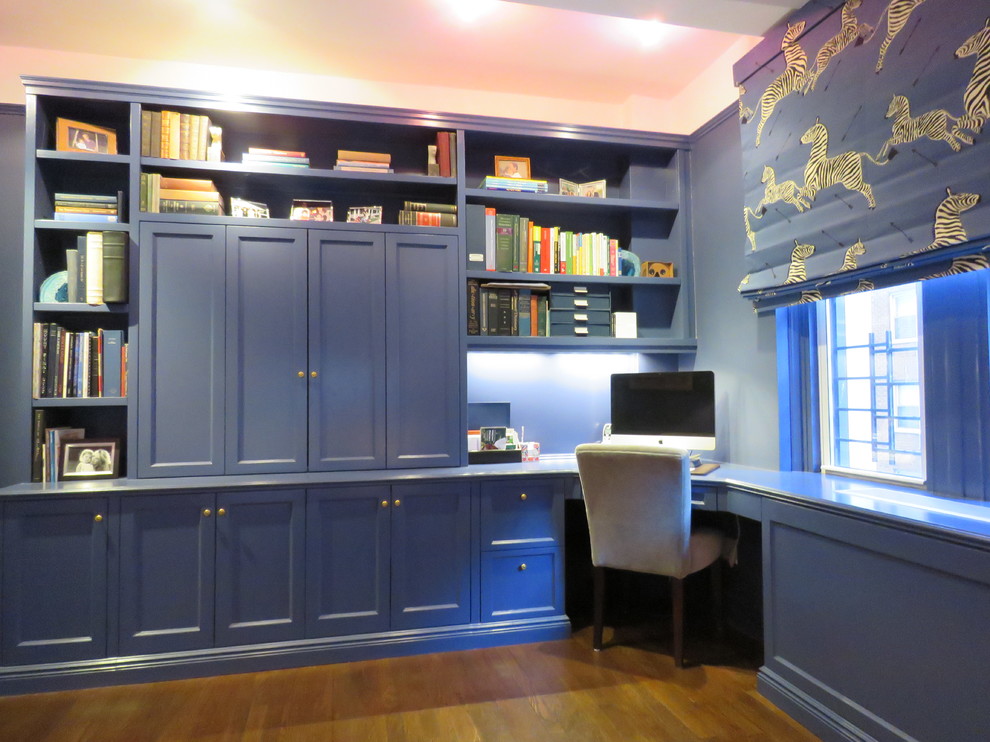 Imagen de sala de estar con biblioteca cerrada tradicional renovada de tamaño medio sin chimenea y televisor con paredes azules, suelo de madera oscura y suelo marrón