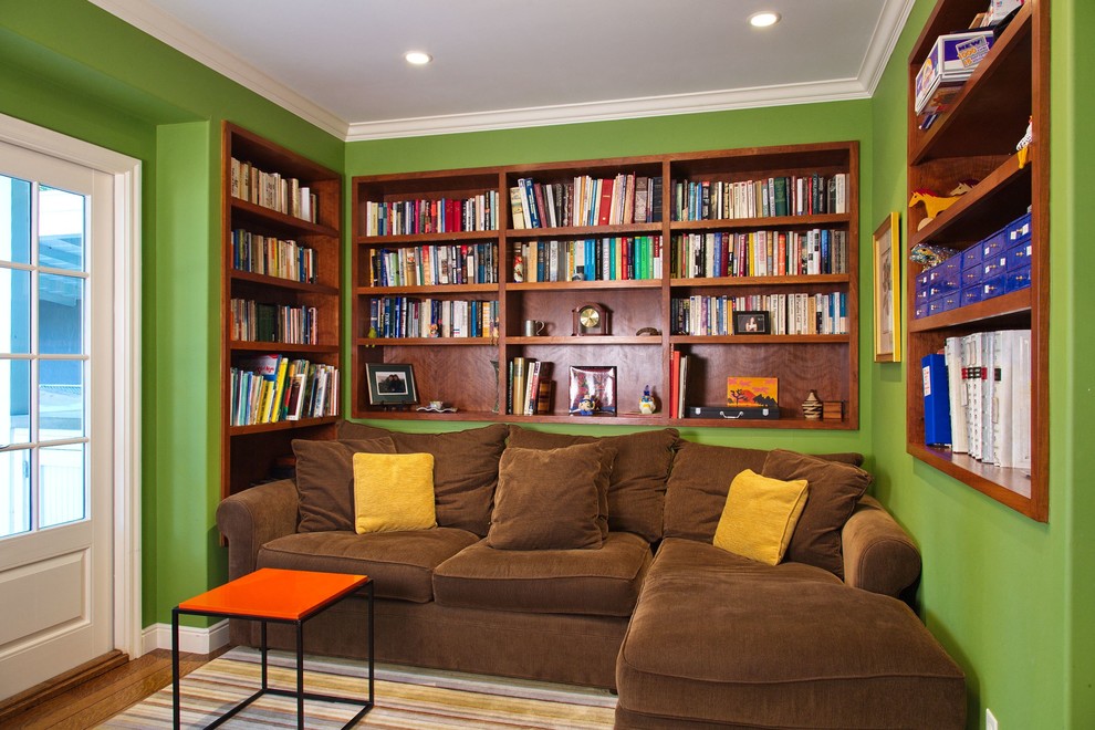 Modelo de sala de estar con biblioteca cerrada contemporánea con paredes verdes y suelo de madera en tonos medios