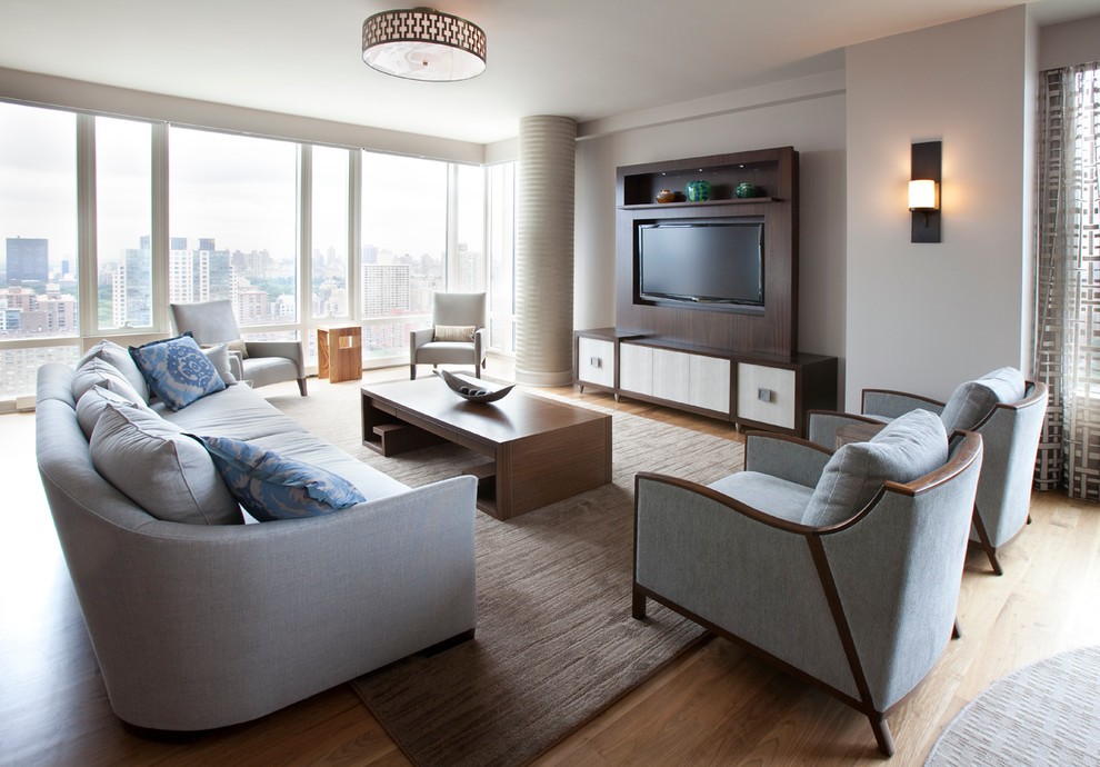 Diseño de sala de estar abierta contemporánea de tamaño medio sin chimenea con paredes grises, suelo de madera clara y pared multimedia