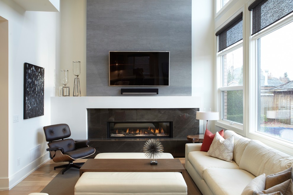 Imagen de sala de estar abierta moderna de tamaño medio con paredes blancas, suelo de madera clara, chimenea lineal, marco de chimenea de baldosas y/o azulejos y televisor colgado en la pared