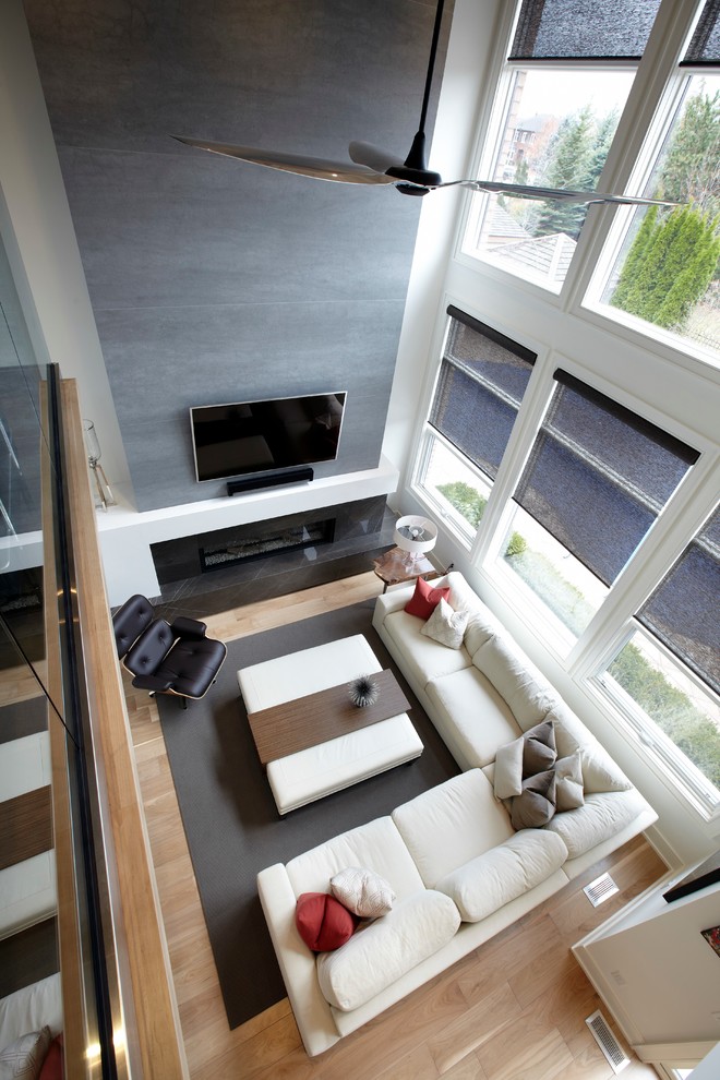 Modelo de sala de estar abierta moderna de tamaño medio con paredes blancas, suelo de madera clara, chimenea lineal, marco de chimenea de baldosas y/o azulejos y televisor colgado en la pared