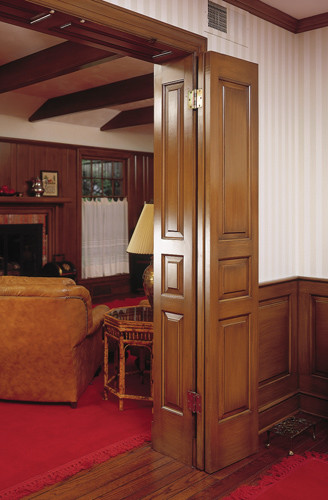 Example of a classic enclosed medium tone wood floor family room design in New York with white walls, a standard fireplace and a wood fireplace surround