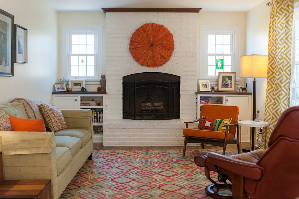 Example of a trendy medium tone wood floor and brown floor family room design in Wilmington with beige walls, a standard fireplace and a brick fireplace