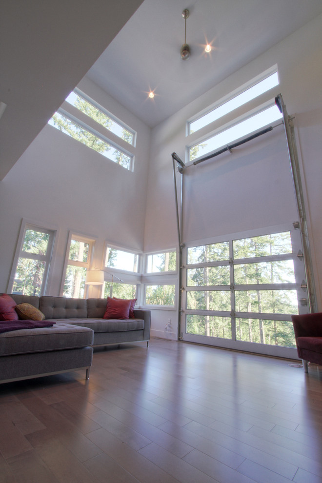 Immagine di un soggiorno moderno di medie dimensioni e aperto con pareti grigie, pavimento in legno massello medio e parete attrezzata