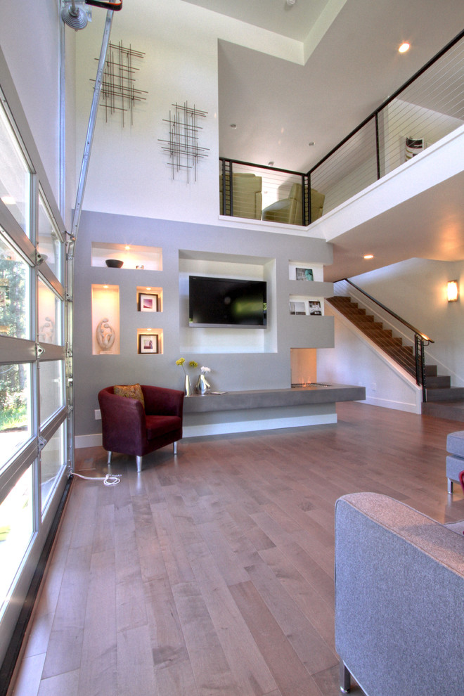 Exemple d'une salle de séjour moderne de taille moyenne et ouverte avec un sol en bois brun, un manteau de cheminée en béton, un téléviseur fixé au mur, un mur multicolore et une cheminée d'angle.