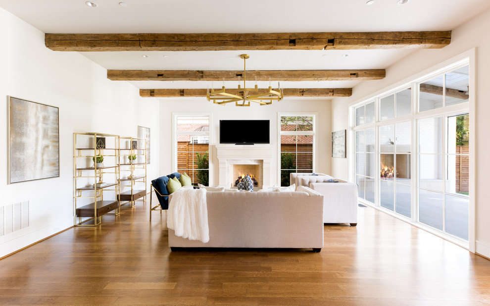 Modelo de sala de estar tradicional renovada con paredes beige, suelo de madera en tonos medios, todas las chimeneas y televisor colgado en la pared