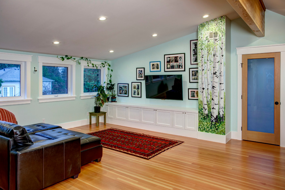 Cette photo montre une grande salle de séjour nature avec un mur vert, un sol en bois brun et un téléviseur fixé au mur.