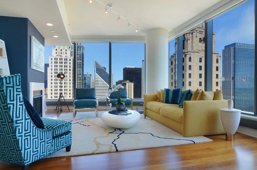 Offenes Modernes Wohnzimmer mit blauer Wandfarbe, braunem Holzboden, Kamin und Kaminumrandung aus Stein in Chicago