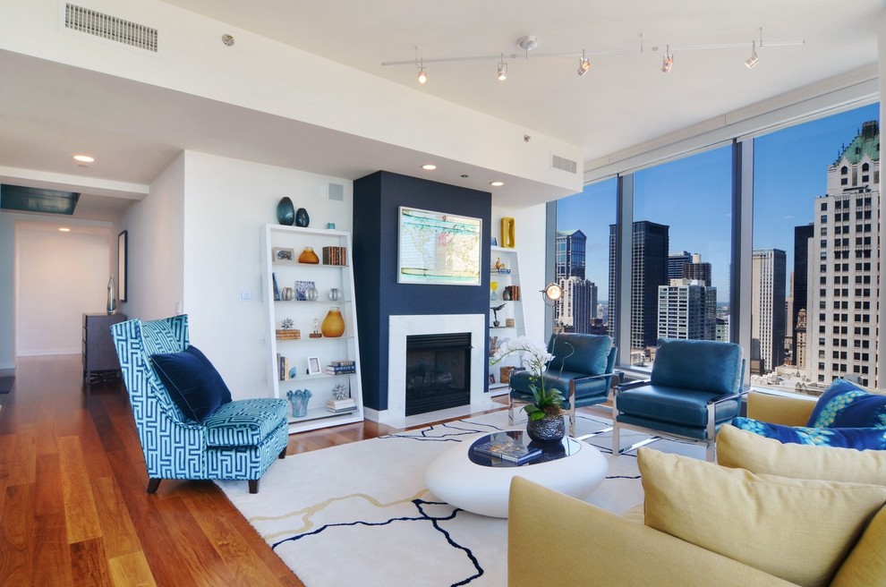 Offenes Modernes Wohnzimmer mit weißer Wandfarbe, braunem Holzboden, Kamin und Kaminumrandung aus Stein in Chicago