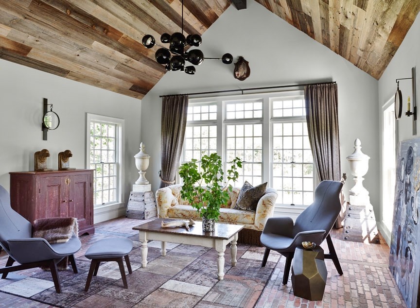 Imagen de sala de estar cerrada de estilo de casa de campo grande sin chimenea con paredes beige, suelo de ladrillo y televisor colgado en la pared