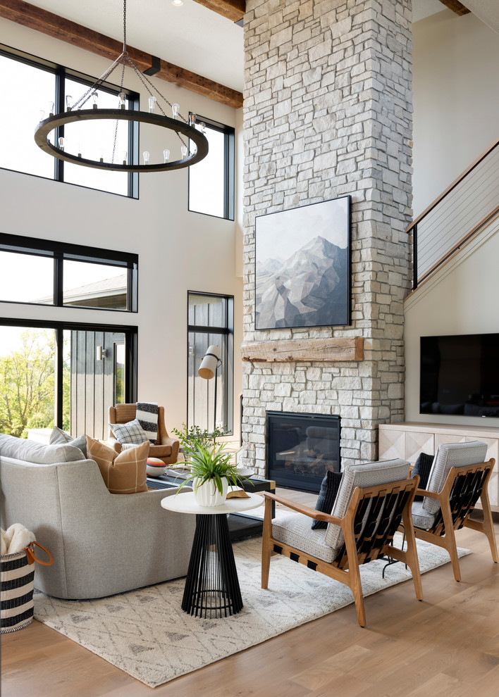 Diseño de sala de estar contemporánea con paredes blancas, suelo de madera en tonos medios, todas las chimeneas, marco de chimenea de piedra, televisor colgado en la pared y suelo marrón