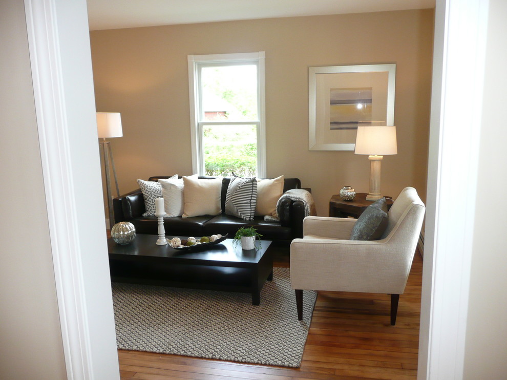 Imagen de sala de estar cerrada clásica renovada de tamaño medio sin chimenea con paredes beige, suelo de madera en tonos medios y televisor colgado en la pared