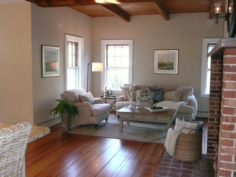 Mittelgroßes, Fernseherloses, Offenes Landhaus Wohnzimmer mit beiger Wandfarbe, braunem Holzboden, Kamin und Kaminumrandung aus Backstein in Boston
