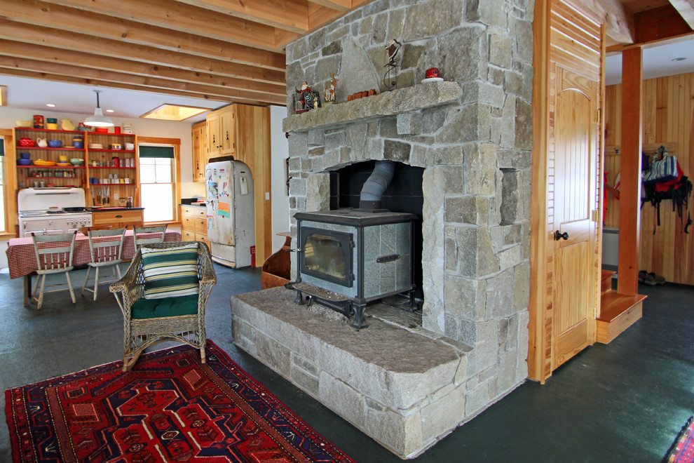 Ejemplo de sala de estar abierta rural de tamaño medio con todas las chimeneas, marco de chimenea de piedra, paredes blancas, suelo de cemento y suelo negro