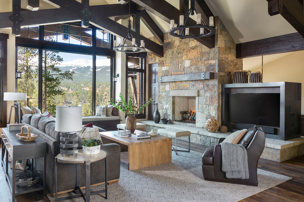 Design ideas for a large rustic enclosed games room in Denver with white walls, a standard fireplace, a stone fireplace surround, a wall mounted tv, brown floors, dark hardwood flooring and feature lighting.