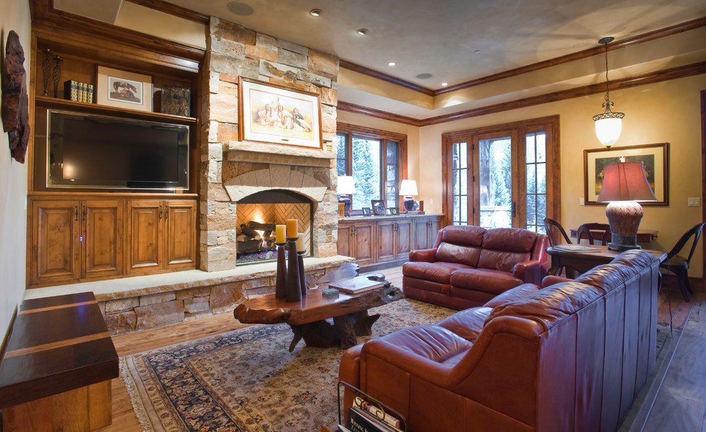 Mittelgroßes, Abgetrenntes Rustikales Wohnzimmer mit beiger Wandfarbe, braunem Holzboden, Kamin, Kaminumrandung aus Stein und Multimediawand in Denver