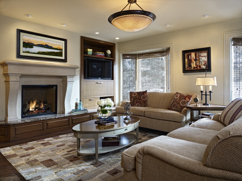 Klassisches Wohnzimmer mit beiger Wandfarbe, dunklem Holzboden, Kamin, Kaminumrandung aus Stein und Multimediawand in Denver