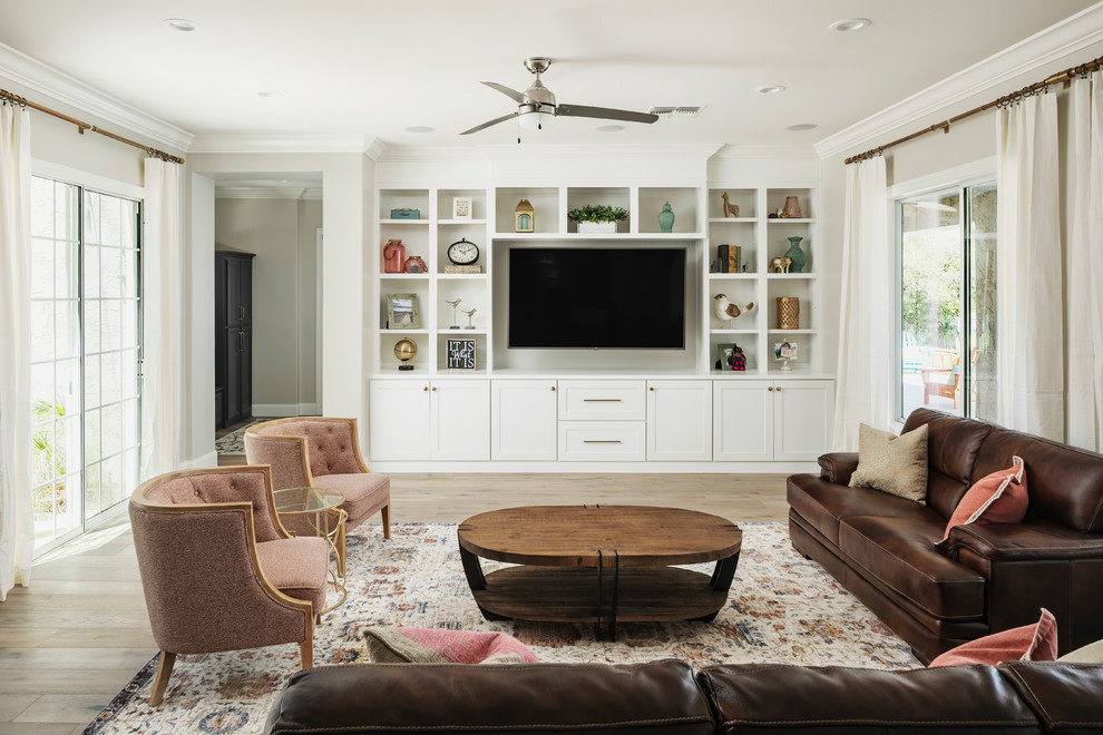 Imagen de sala de estar con biblioteca abierta tradicional renovada grande con paredes beige, suelo de madera clara, pared multimedia y suelo beige