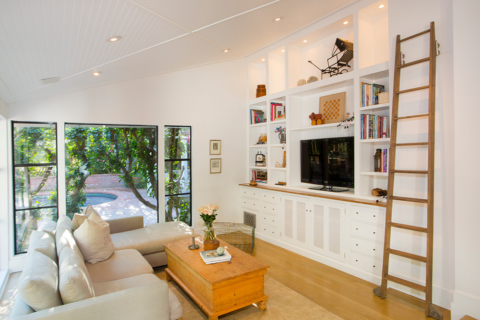 Modelo de sala de estar ecléctica con paredes blancas, pared multimedia y suelo de madera clara