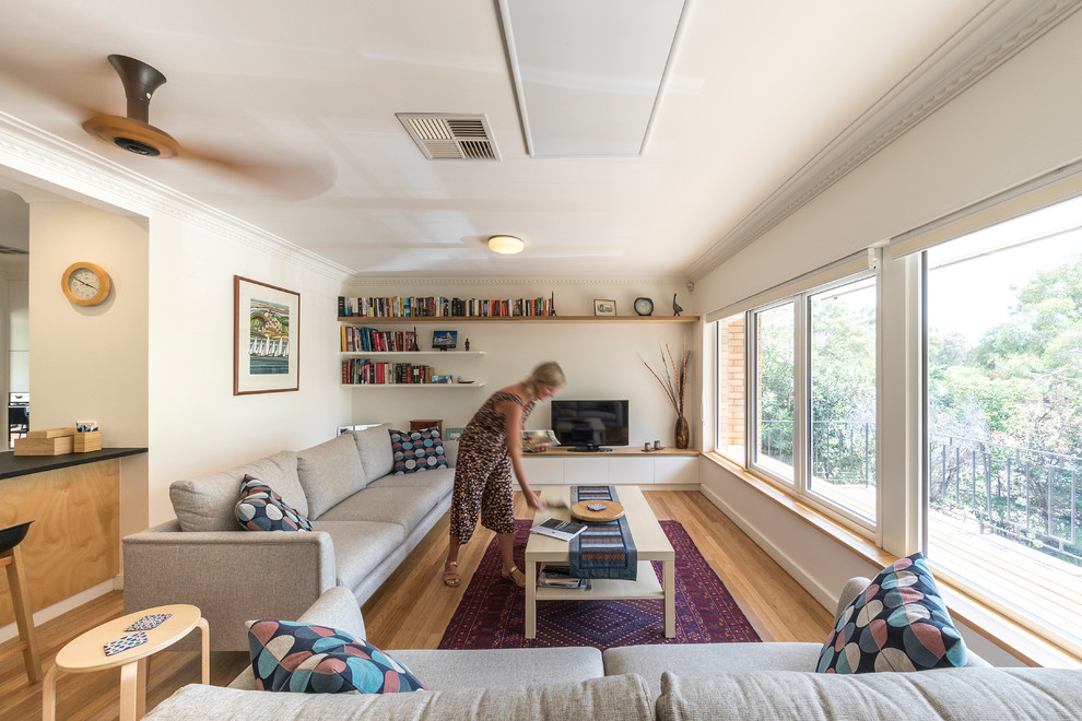Ejemplo de sala de estar abierta contemporánea de tamaño medio con paredes blancas, suelo de madera clara, televisor independiente y suelo amarillo