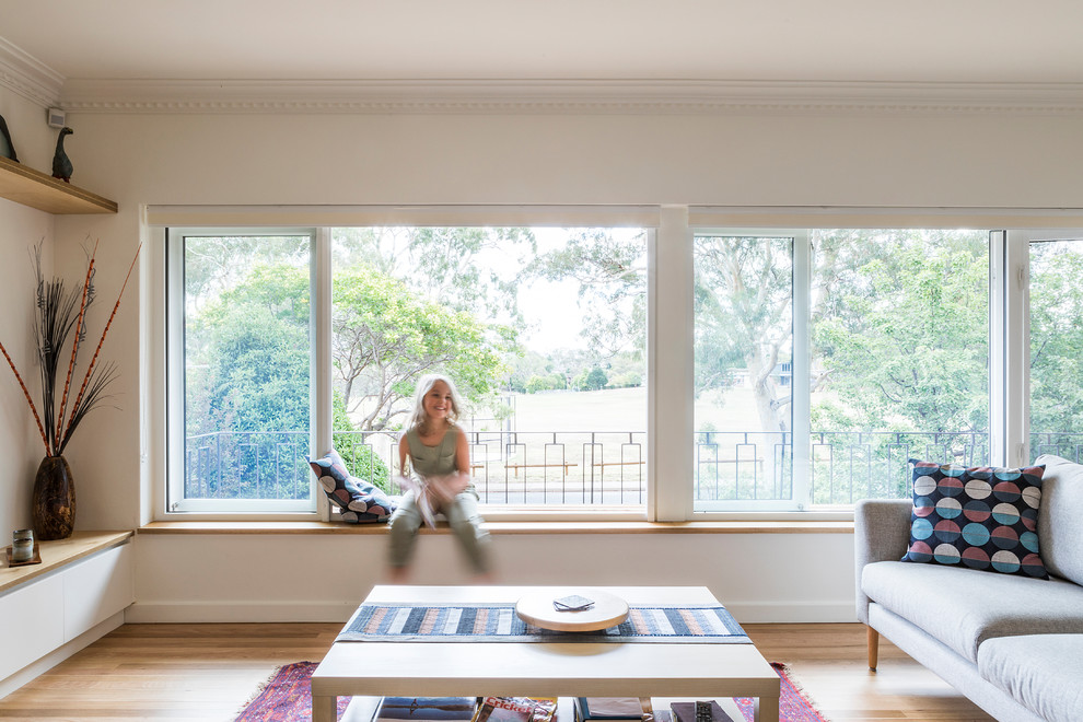 Mittelgroßes, Offenes Modernes Wohnzimmer mit weißer Wandfarbe, hellem Holzboden, freistehendem TV und gelbem Boden in Canberra - Queanbeyan