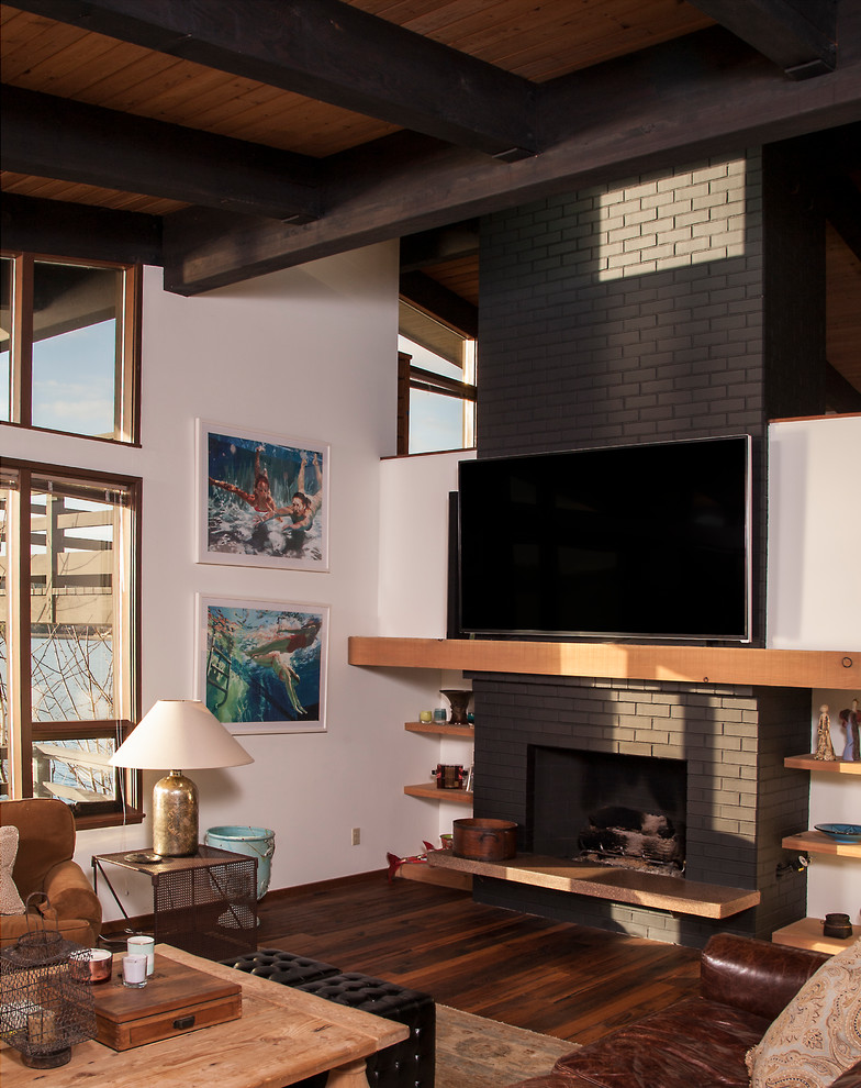 シアトルにある広いコンテンポラリースタイルのおしゃれなオープンリビング (白い壁、濃色無垢フローリング、標準型暖炉、レンガの暖炉まわり、壁掛け型テレビ、茶色い床) の写真