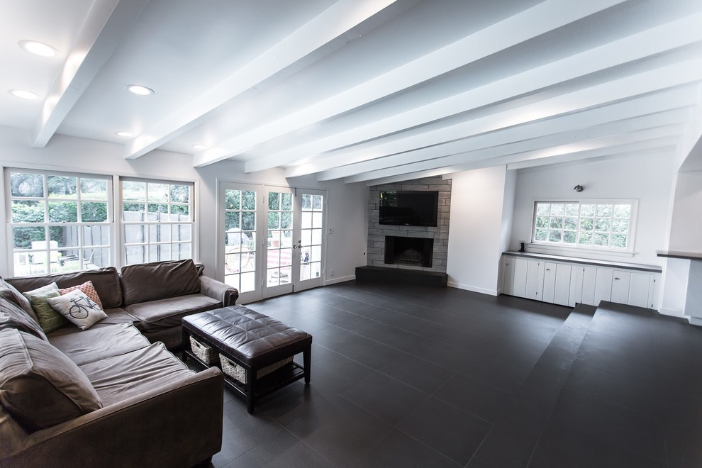 На фото: огромная открытая гостиная комната в стиле модернизм с белыми стенами, полом из керамогранита, угловым камином, фасадом камина из плитки и телевизором на стене