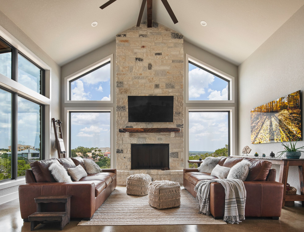 Diseño de sala de estar tradicional renovada con paredes grises, televisor colgado en la pared, suelo de cemento, todas las chimeneas, marco de chimenea de piedra, suelo marrón y alfombra