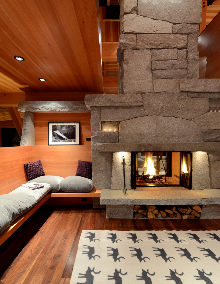 Modelo de sala de estar rural con paredes marrones, suelo de madera oscura, chimenea de doble cara, marco de chimenea de piedra y suelo marrón