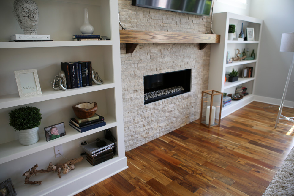 Imagen de sala de estar abierta bohemia grande con suelo de madera clara, todas las chimeneas, marco de chimenea de piedra y televisor colgado en la pared