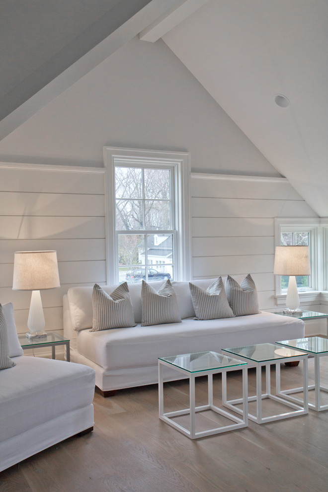 Example of a mid-sized cottage light wood floor family room design in New York with white walls and no fireplace