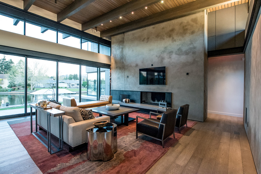 Großes, Offenes Modernes Wohnzimmer mit grauer Wandfarbe, braunem Holzboden, Gaskamin, TV-Wand, Kaminumrandung aus Beton und braunem Boden in Seattle