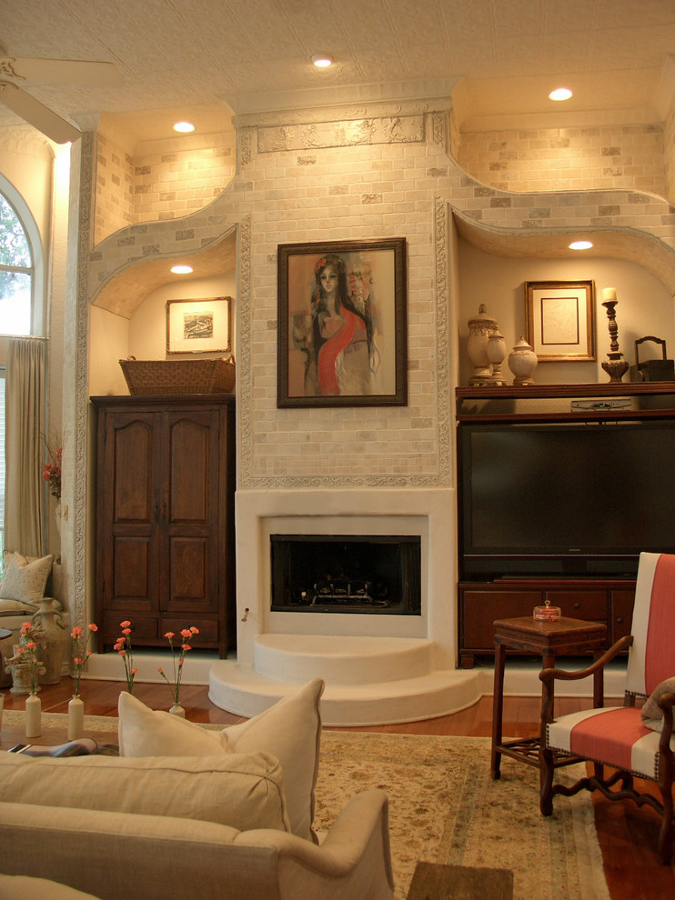 Imagen de sala de estar tradicional con paredes beige, suelo de madera en tonos medios, todas las chimeneas y televisor independiente