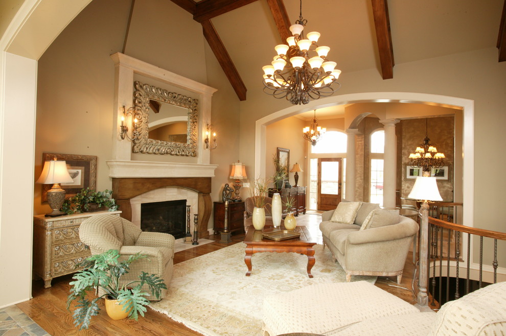 Imagen de sala de estar abierta tradicional grande con paredes beige, suelo de madera clara, todas las chimeneas y marco de chimenea de piedra