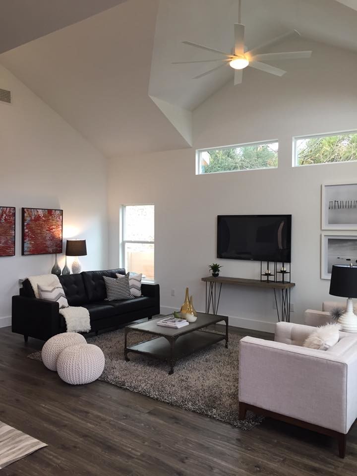 Diseño de sala de estar abierta actual de tamaño medio con paredes blancas, suelo de madera oscura, televisor colgado en la pared y suelo marrón
