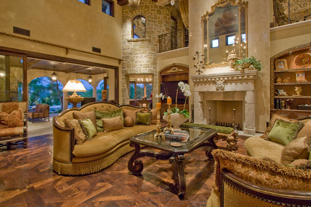 Offenes Mediterranes Wohnzimmer mit beiger Wandfarbe, braunem Holzboden, Kamin und Kaminumrandung aus Stein in Los Angeles