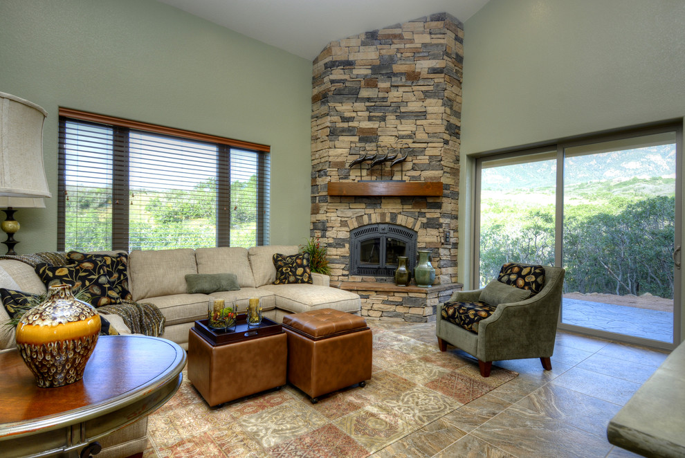На фото: большая открытая гостиная комната в классическом стиле с зелеными стенами, полом из травертина, угловым камином и фасадом камина из камня без телевизора с