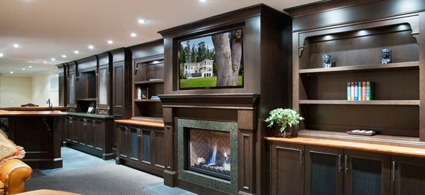 Large contemporary open plan games room in Vancouver with a home bar, beige walls, carpet, a standard fireplace, a wooden fireplace surround, a wall mounted tv and grey floors.
