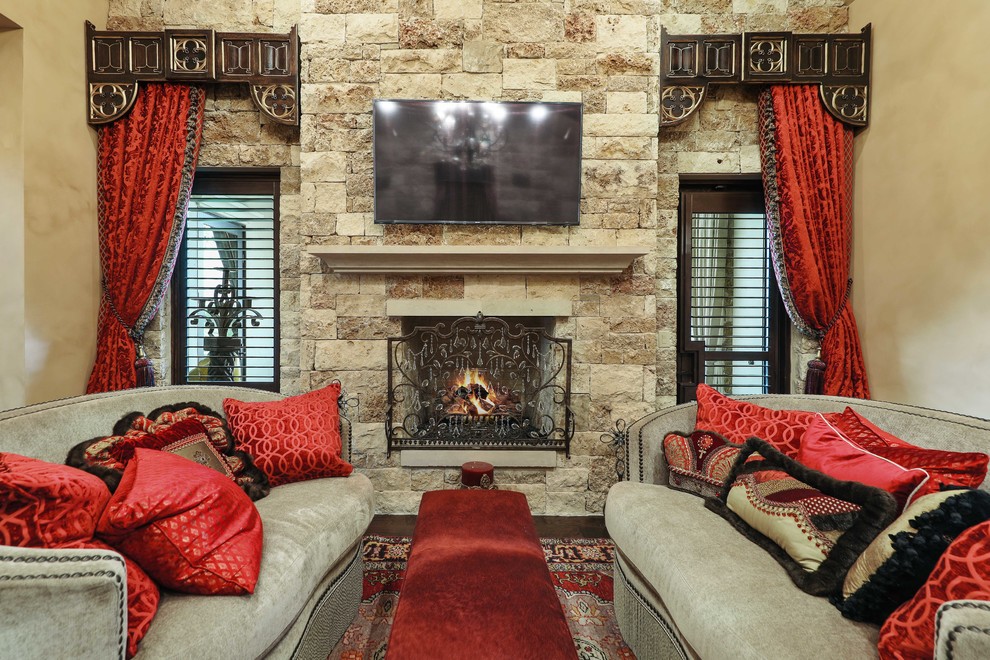 Design ideas for a mediterranean games room in Austin with beige walls, dark hardwood flooring, a standard fireplace, a stone fireplace surround and a wall mounted tv.