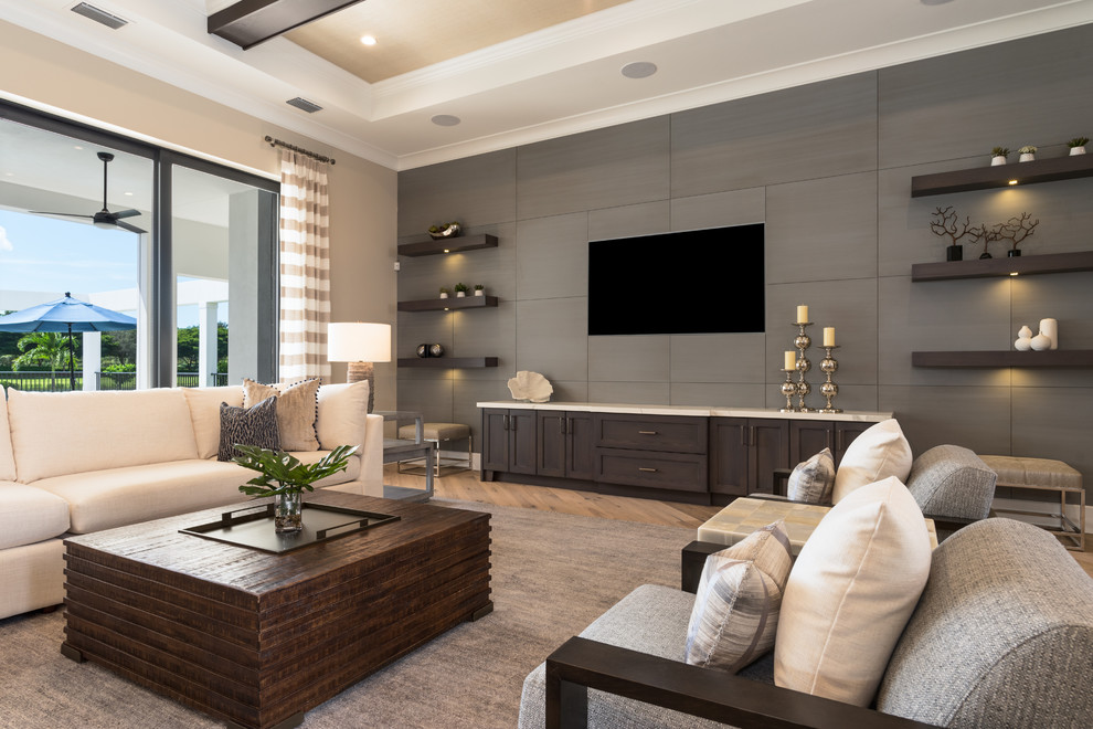 Diseño de sala de estar abierta clásica renovada extra grande sin chimenea con paredes beige, suelo de madera clara, televisor colgado en la pared y alfombra