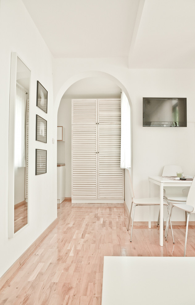 Foto de sala de estar tipo loft mediterránea grande sin chimenea con paredes blancas, suelo de madera en tonos medios y televisor colgado en la pared