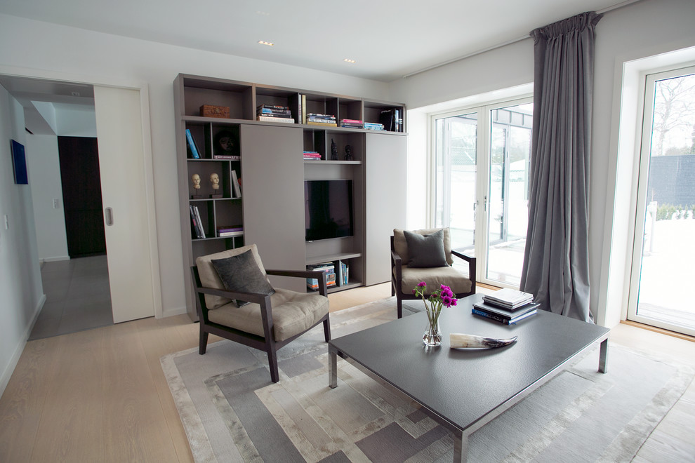 Mittelgroßes, Repräsentatives, Offenes Skandinavisches Wohnzimmer mit grauer Wandfarbe, braunem Holzboden und verstecktem TV in Kopenhagen