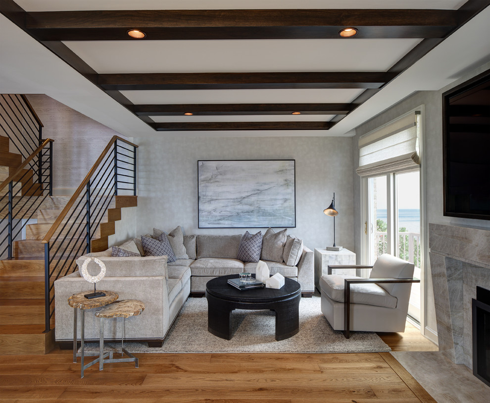 Modelo de sala de estar abierta contemporánea grande con paredes grises, suelo de madera clara, todas las chimeneas y marco de chimenea de piedra