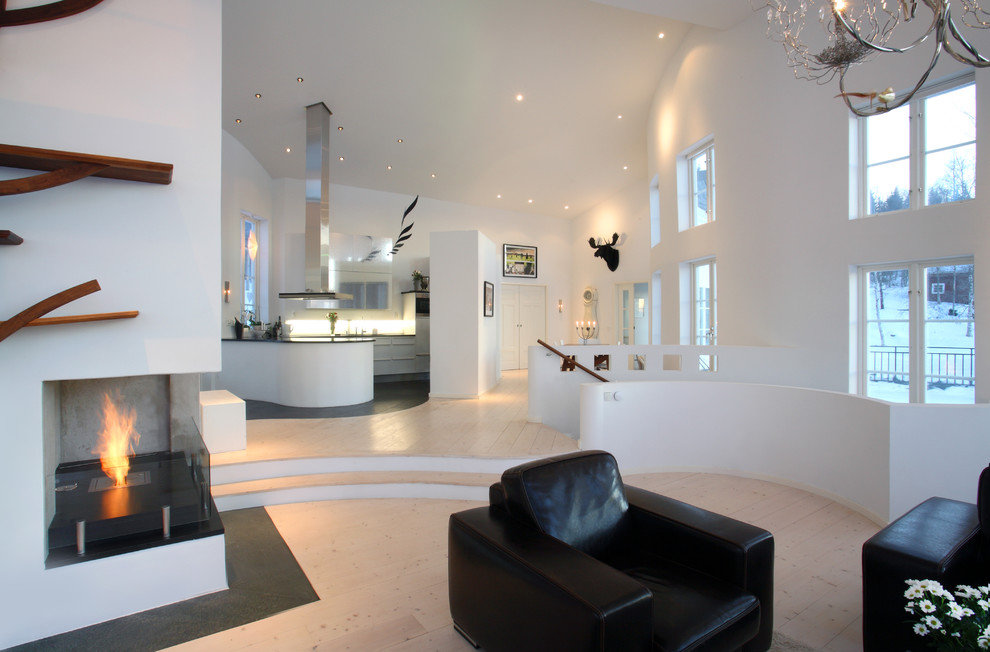 На фото: большая открытая гостиная комната в современном стиле с белыми стенами, светлым паркетным полом, угловым камином, фасадом камина из бетона и отдельно стоящим телевизором