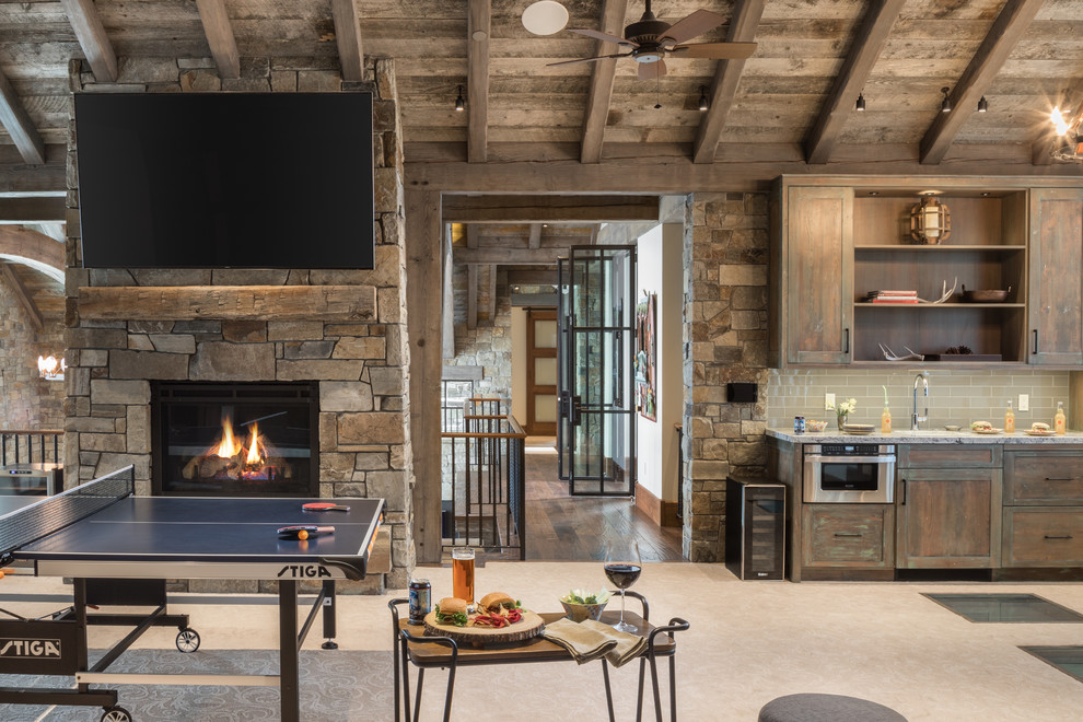 Inspiration for a rustic open concept dark wood floor and brown floor game room remodel in Jackson with a standard fireplace, a stone fireplace and a wall-mounted tv